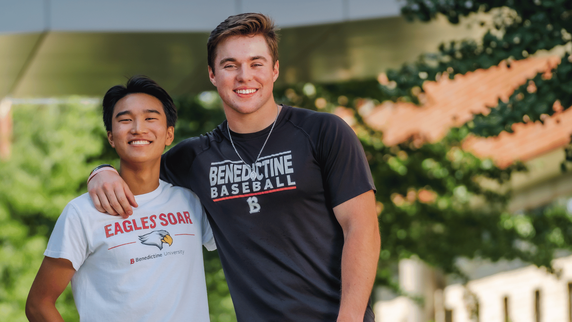 Two young men posing for a picture in front of a building.