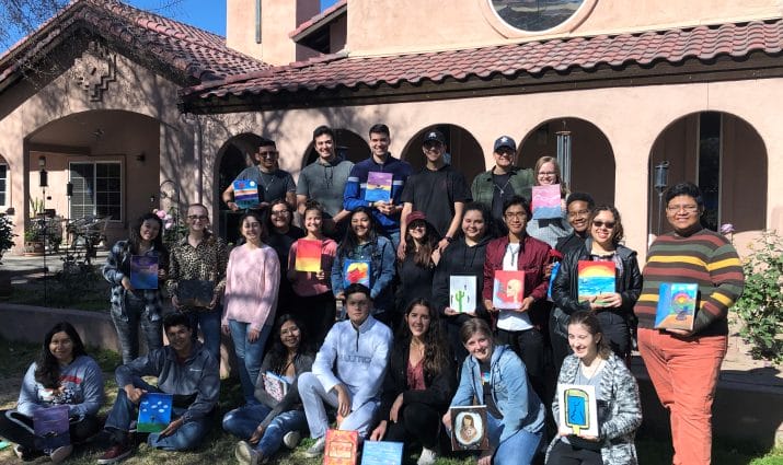 A group of people posing in front of a church holding books.