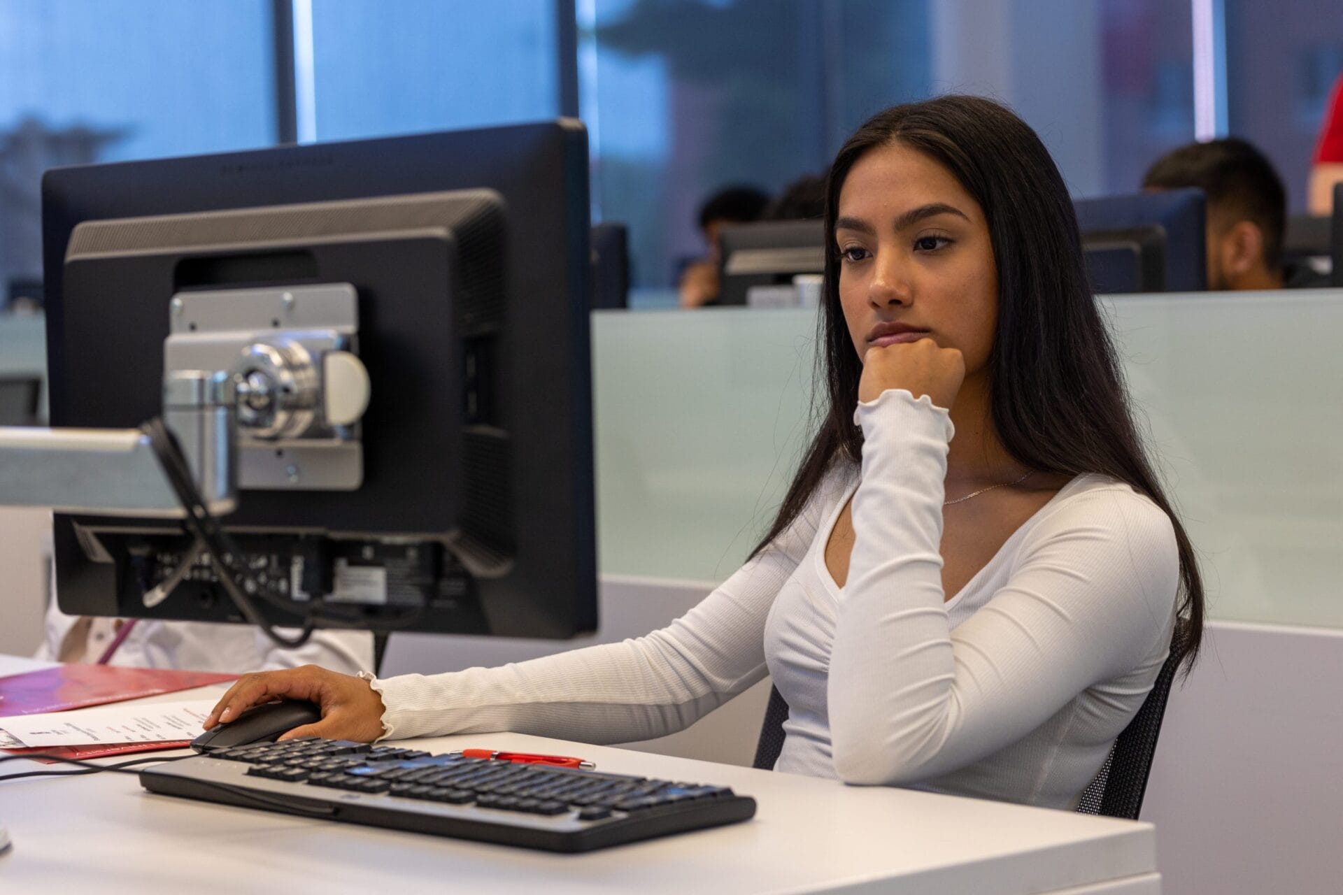 A young woman sitting at a desk in front of a computer.