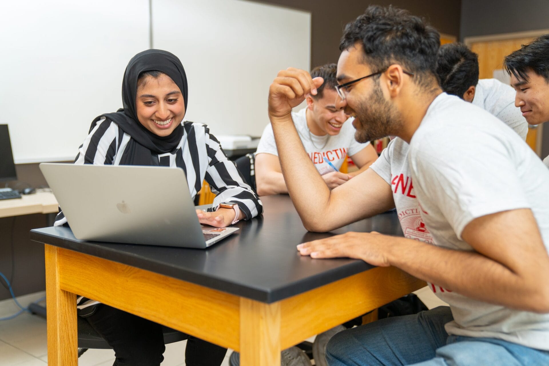 students at table laughing at laptop