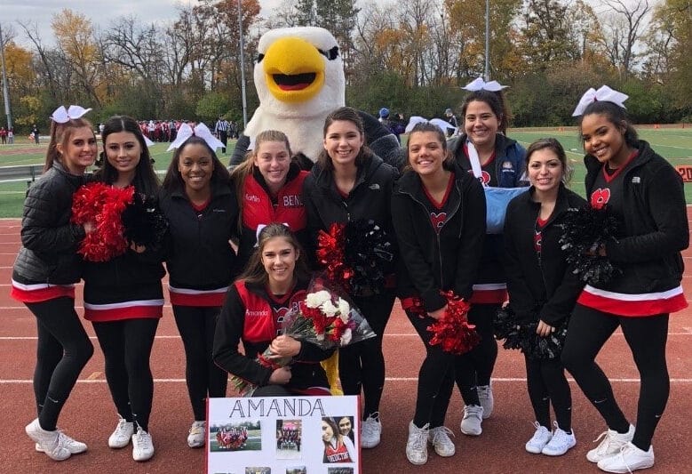 Cheerleaders pose for a photo with an eagle.